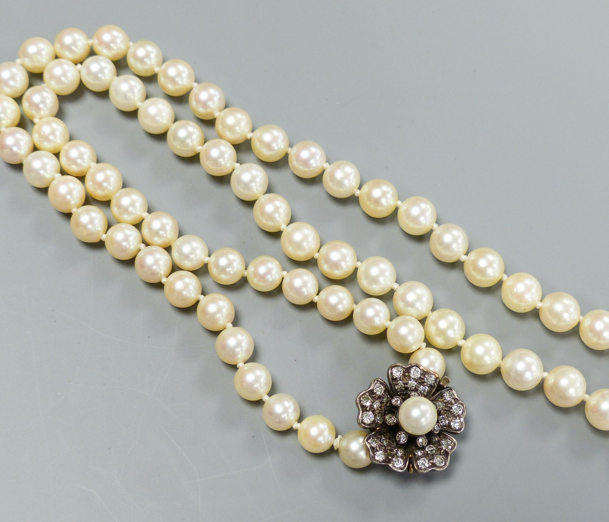 A single strand graduated cultured pearl necklace, with yellow metal, diamond and cultured pearl set flower head cluster clasp, 76cm, largest pearl diameter 94mm, gross weight 66 grams.